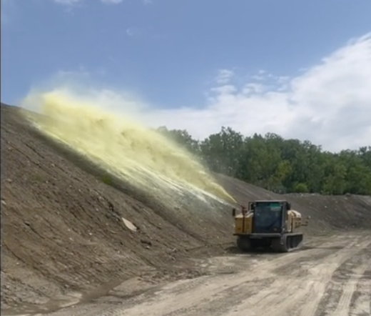 Tracked application vehicle applying material to a slope.